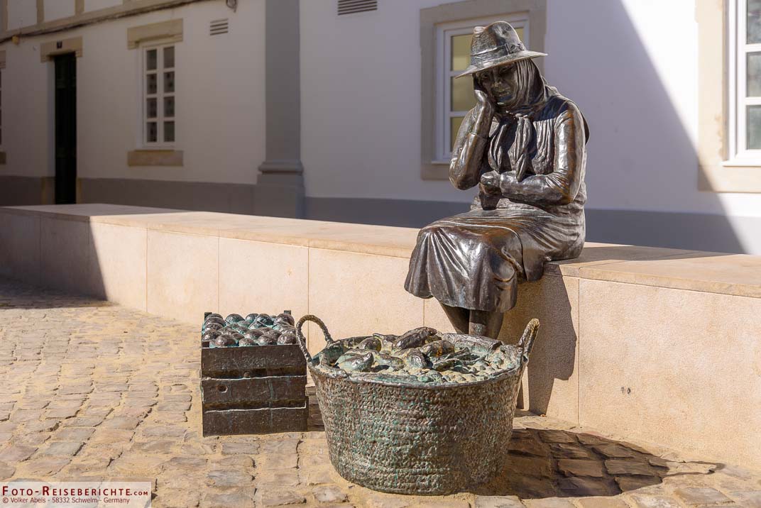 Bronzestatue einer alten portugiesischen Bäuerin mit ihren zum Verkauf stehenden Produkten vor der Markthalle der Stadt,